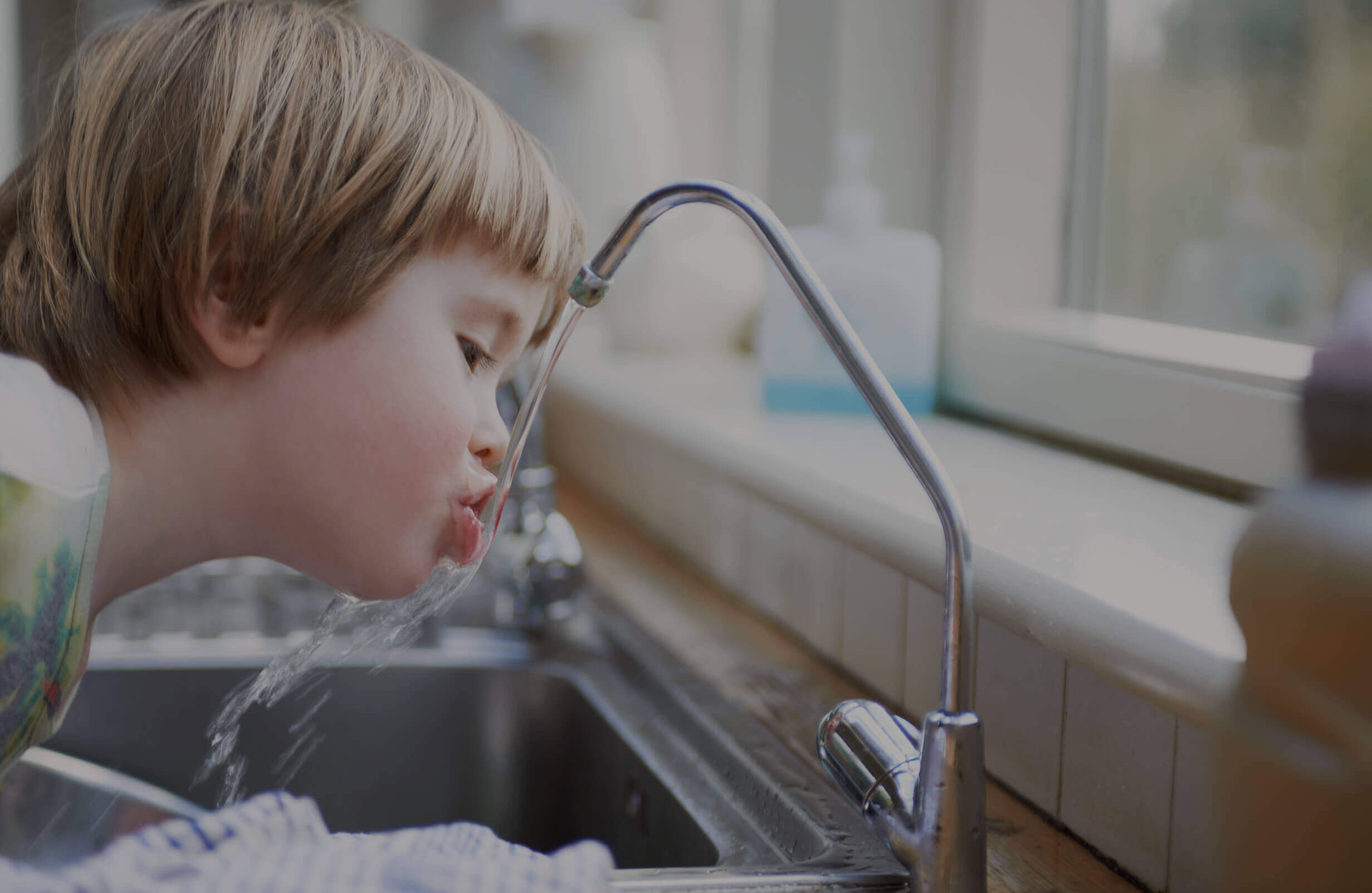 A child drinking from a faucet