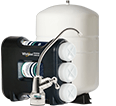 A reverse osmosis water filtration system with multiple filters and a faucet is positioned in front of a large white storage tank.